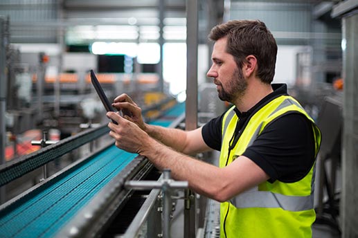 Image of a factory worker using an iPad by a production line